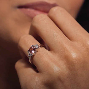 Three stone engagement ring with 1ct cushion cut lab grown champagne pink sapphire center with two moon cut side stones in accented basket style head in 14k white gold shown worn on hand