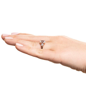 Three stone engagement ring with 1ct oval cut lab grown diamond and two round cut lab diamond shoulder stones in basket style 14k rose gold setting worn on hand sideview