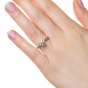 Solitaire engagement ring with 1ct round cut lab grown diamond in cathedral style 14k white gold band worn on hand