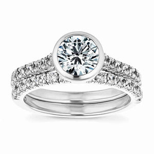  stackable engagement ring Shown with a bezel set 1.0ct Round cut Lab-Grown Diamond with accenting stones on the band in recycled 14K white gold with matching wedding band