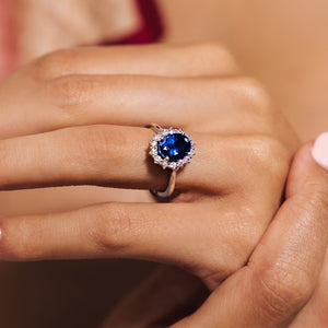 Gorgeous vintage style engagement ring with floral design halo around a 3ct lab grown blue sapphire in 14k white gold worn on hand